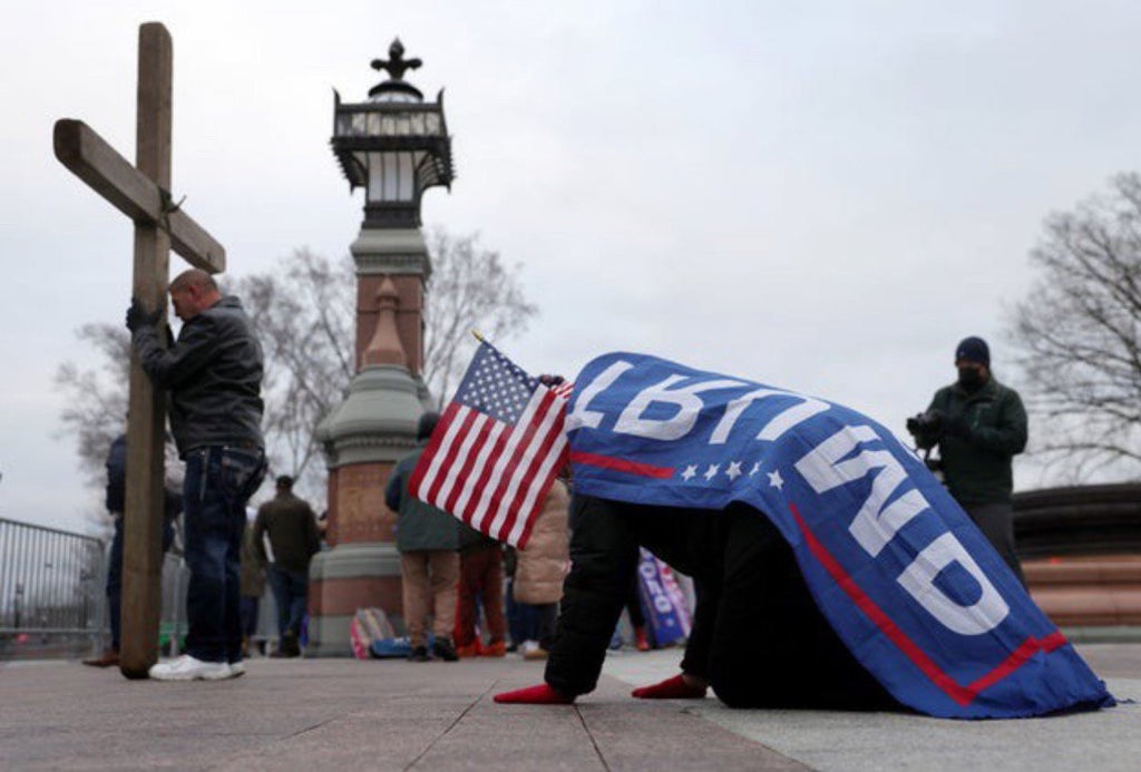 carrying a cross and wrapped in the flag