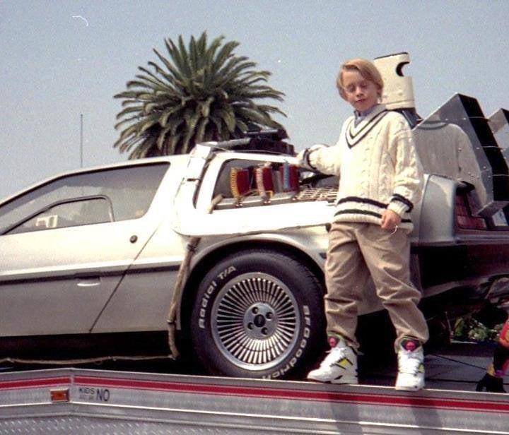 Macaulay Culkin with Reebok pumps leaning on the most iconic car of the 80s